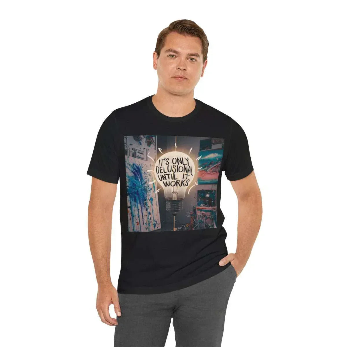Man wearing black graphic tee with 'It's only delusional until it works' lightbulb design