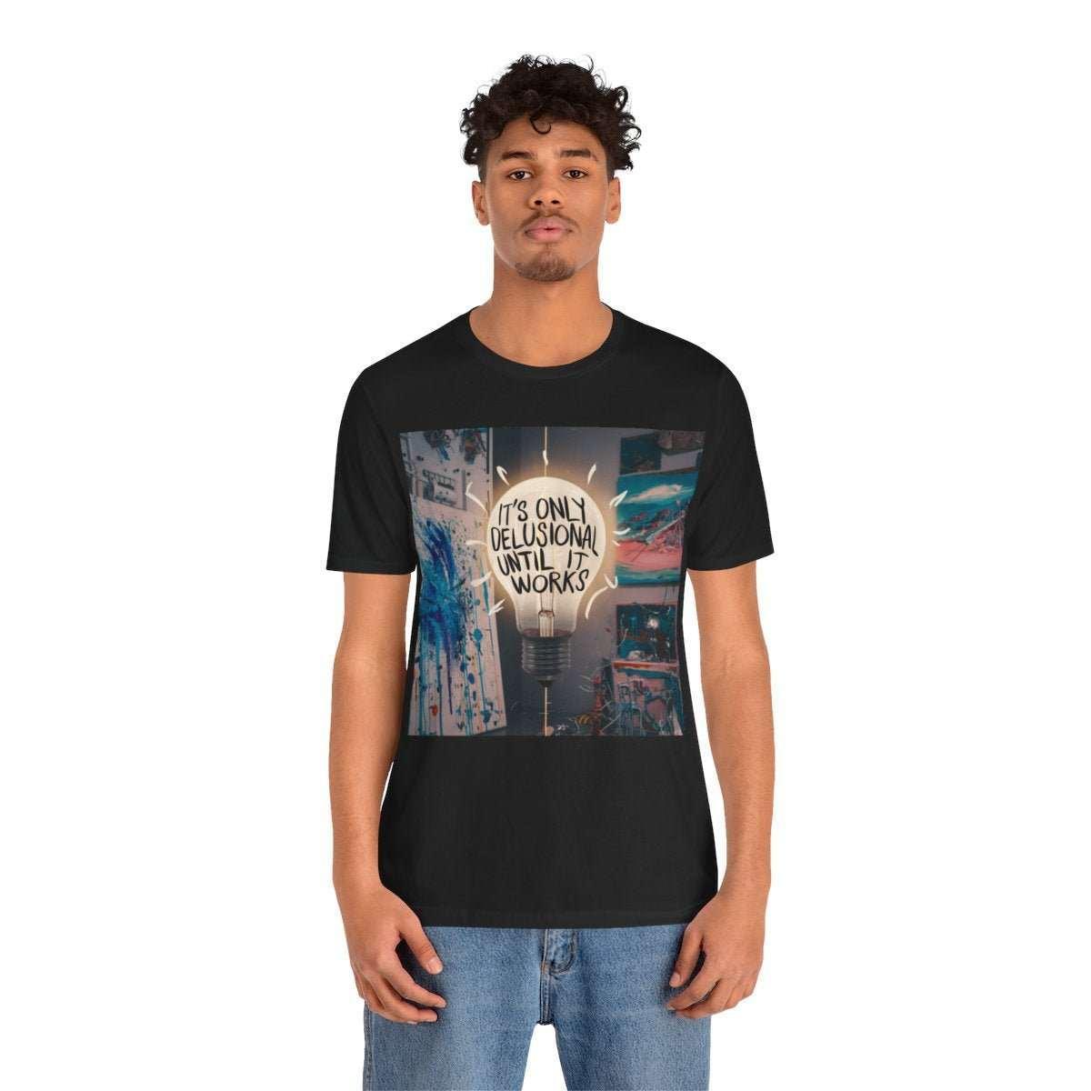 Man wearing black graphic tee with light bulb art and 'It's only delusional until it works' text.