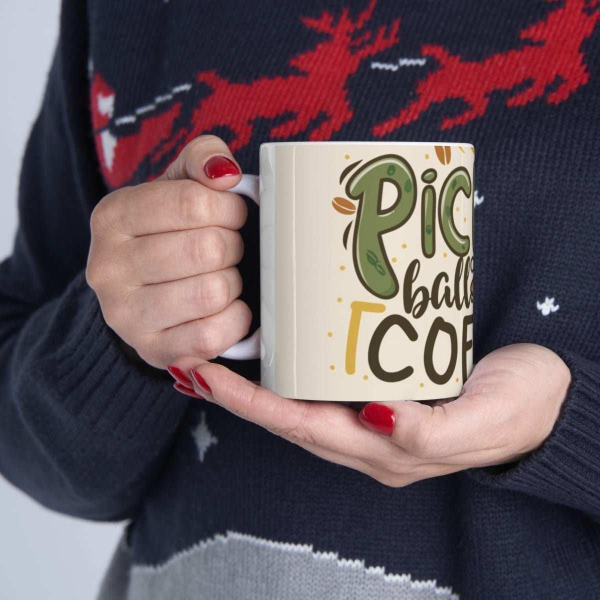 Hand holding ceramic mug with pickleball coffee design, person wearing festive sweater.